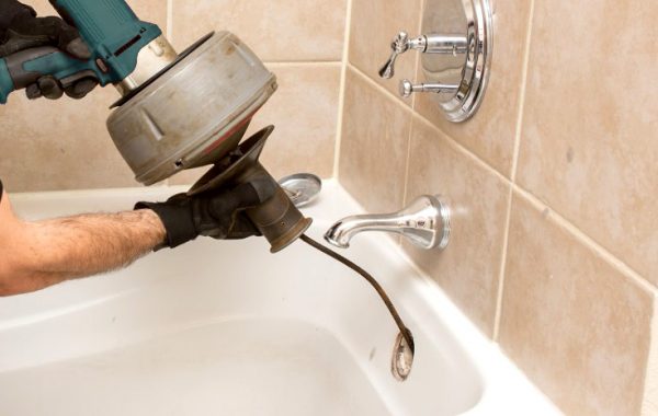 plumber unclogs a bathtub